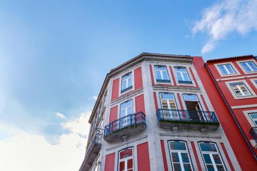 a red brick building with windows and a blue sky at Chateau Apartments in Porto