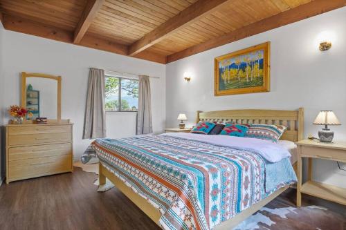 a bedroom with a bed and a desk and a window at Taos Pine Home in Taos