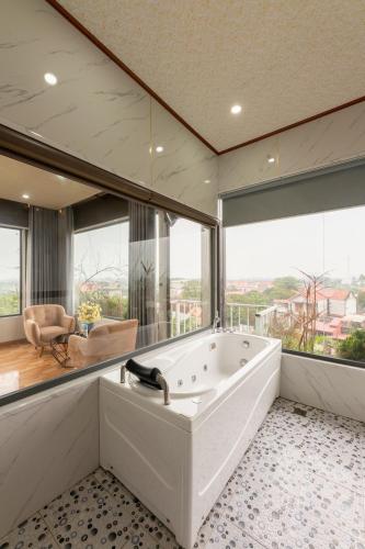 a large white bath tub in a room with large windows at TAM COC SUNSHINE HOTEL in Ninh Binh