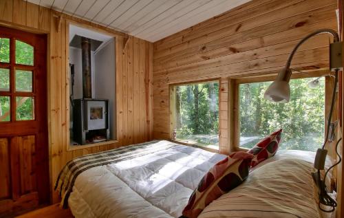 a bed in a room with wooden walls and windows at Casita Arbol in Puerto Fuy