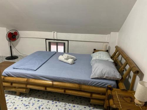 a bedroom with a wooden bed with towels on it at Koa's Beach House in Tangalan