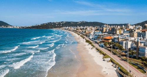 a view of a beach with buildings and the ocean at Residencial DO MAR in Bombinhas