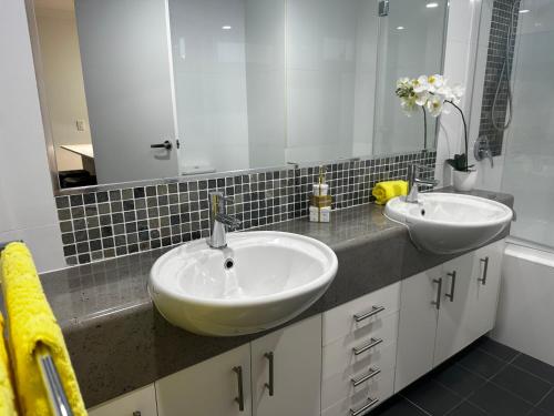 a bathroom with two sinks and a large mirror at Broadwater Parklands Paradise in Gold Coast