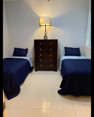 a bedroom with two beds and a dresser and a lamp at Blue Hideaway With Shared Spaces in Riviera Beach