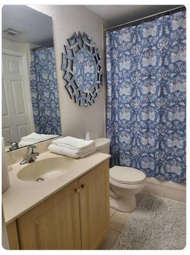 a bathroom with a sink and a toilet and a mirror at Blue Hideaway With Shared Spaces in Riviera Beach