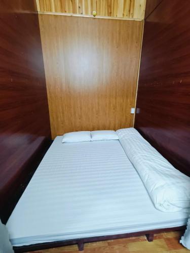 a bed in a room with a wooden wall at Moc's House bắc hà in Bắc Hà