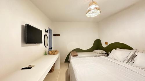 a bedroom with two beds and a tv on the wall at Pousada Vilab in Arraial d'Ajuda