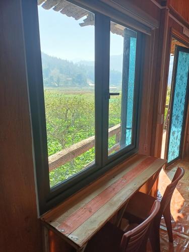 a window with a table and a view of a field at Moc's House bắc hà in Bắc Hà