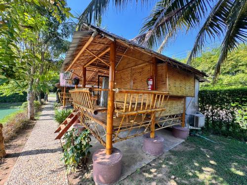 a small wooden house with a porch and palm trees at ข้าวทุ่งเบ็ญจาโฮมสเตย์ in Ban Hat Phang