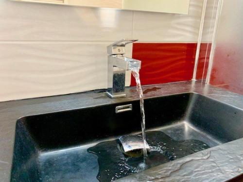 d'un évier de cuisine avec de l'eau provenant d'un robinet. dans l'établissement Splendide T3 près de la mer avec piscine, parking et Wi-Fi - FR-1-607-206, au Cap d'Agde