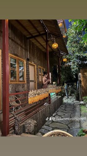 a woman standing in front of a wooden building at Moc's House bắc hà in Bắc Hà