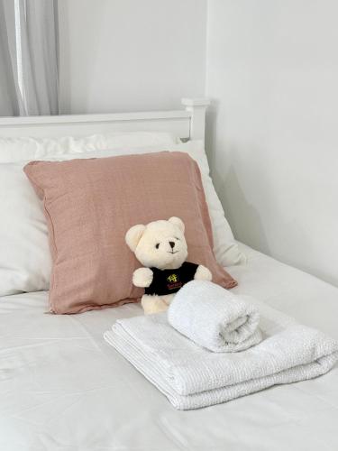 a teddy bear sitting on a bed next to a pillow at Oceanview 3-Bedroom Villa with Garden, Deck, Full Kitchen & WiFi in Halletts Cove
