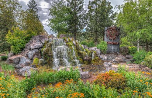 a waterfall in a garden with a sign and flowers at Towhee - Unit 5 in Sunriver