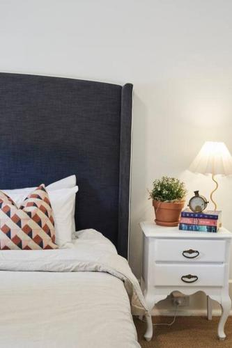 a bed with a black headboard and a night stand with a plant at Little Terrace Bowral 1 in Bowral