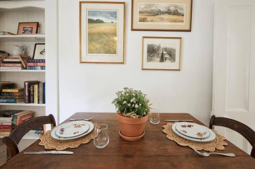 a dining room table with two plates and a potted plant at Little Terrace Bowral 1 in Bowral