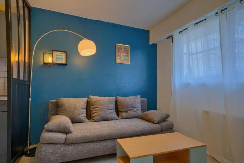 un salon avec un canapé et un mur bleu dans l'établissement Charmant Appartement, En Plein Centre , Face à la Gare Centrale, NICE CENTRE, à Nice