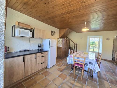 une cuisine avec une table et un réfrigérateur blanc dans l'établissement Charmante Maison Périgourdine avec Jardin Clos, Cheminée et à Proximité des Sites Préhistoriques - FR-1-616-291, à Grèzes