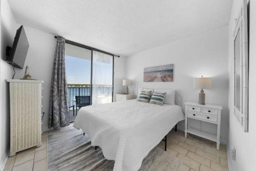 ein weißes Schlafzimmer mit Bett und Balkon in der Unterkunft Gulf Shores Surf & Racquet 716A in Gulf Shores