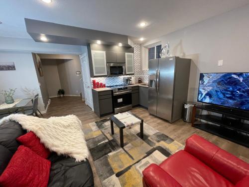 a living room with a red couch and a kitchen at Comfortable and Beautiful Brand-New Suite BSMT-Two Bedroom, Two Washrooms in Calgary