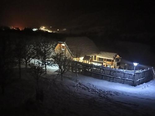 a wooden house in the snow at night at Koliba kod Vukašina in Kremna