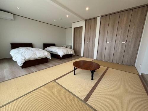 a bedroom with two beds and a table and a bed at OceanフロントYASHIRO鴨川 目の前に海が広がる広々一軒家貸切 11名 in Kamogawa