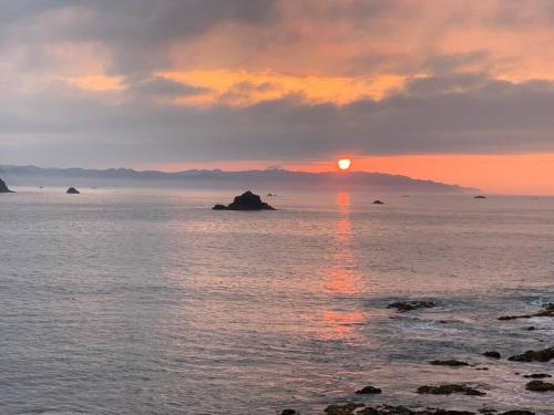 a sunset over the ocean with the sun setting at OceanフロントYASHIRO鴨川 目の前に海が広がる広々一軒家貸切 11名 in Kamogawa