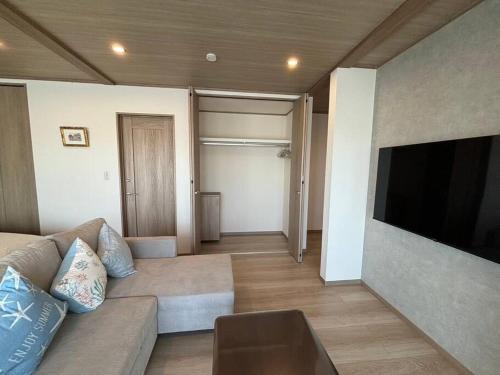 a living room with a couch and a flat screen tv at OceanフロントYASHIRO鴨川 目の前に海が広がる広々一軒家貸切 11名 in Kamogawa