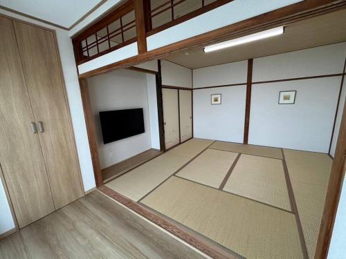 an empty room with a room with a tv in it at OceanフロントYASHIRO鴨川 目の前に海が広がる広々一軒家貸切 11名 in Kamogawa