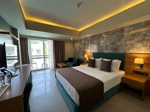 a hotel room with a bed and a television at Ambrosia Hotel Beach & Spa in Bitez