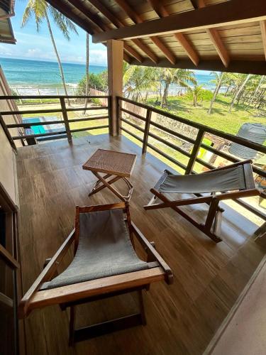 two chairs and a table on a balcony with the ocean at Reef Bungalow Private Villa, 6 bedrooms in Bopitiya