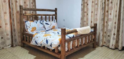 a wooden bed in a bedroom with curtains at LakeSide Beach in Kigoma