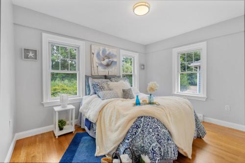 une chambre blanche avec un lit et deux fenêtres dans l'établissement COZY, MODERN, Charming Cottage 1min to the beach, à Quincy