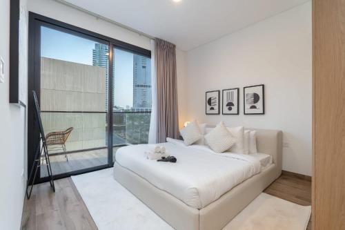a bedroom with a large white bed and a large window at Free housekeeping visits during your stay - StayShort - Stylish, Minimalist 2-Bedroom in Jumeirah Village Circle in Dubai