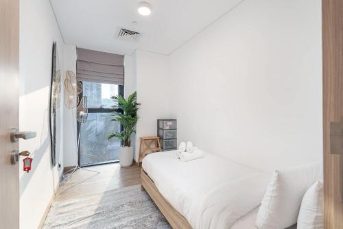 a bedroom with a white bed and a window at Free housekeeping visits during your stay - StayShort - Stylish, Minimalist 2-Bedroom in Jumeirah Village Circle in Dubai