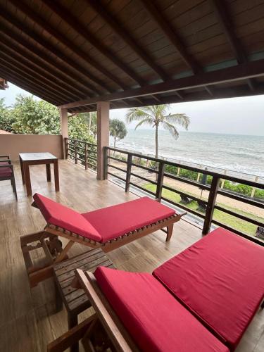 a deck with red cushions and a view of the ocean at Reef Bungalow Private Villa, 6 bedrooms in Bopitiya