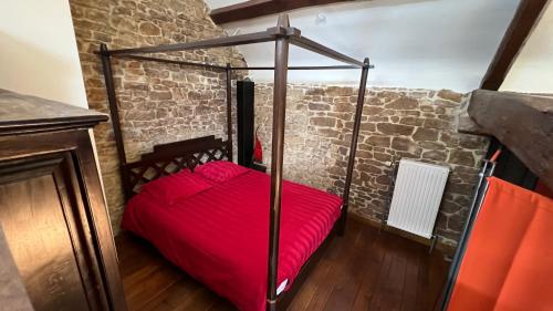 a red bed in a room with a brick wall at Grange de la Rochette - 1 à 6p in Jamoigne