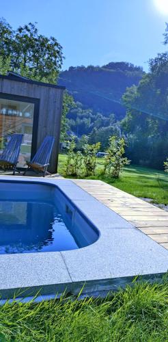 a swimming pool with two chairs and a wooden deck at Le mazot d’Edouard et Celestin in Profondeville