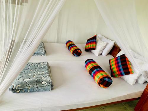 a white bed with four pillows on it at The Rock Face in Ella