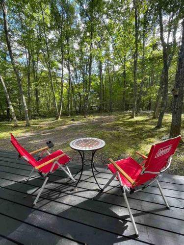two chairs and a table on a deck at Villa Tocca北軽井沢ヴィラ トッカ in Kita-karuizawa