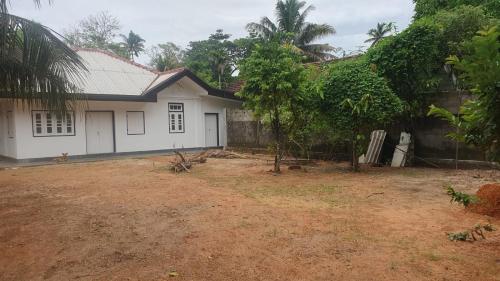 a white house with a wall and a yard at Madiha Sampath Surf Villa in Matara