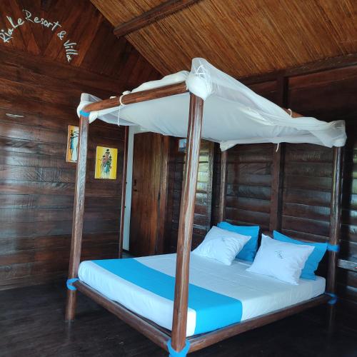 a bed with a canopy in a room with wooden walls at Hotel Ecolodge Riake Resort & Villa in Sainte Marie