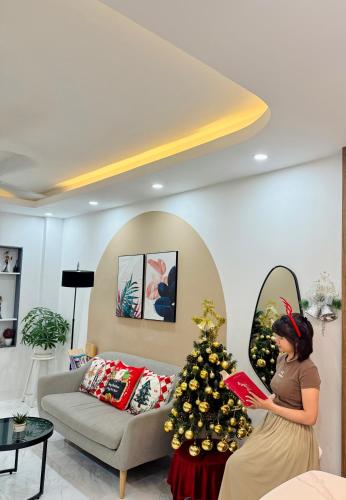a woman standing in a living room with a christmas tree at NalSol House in Hanoi