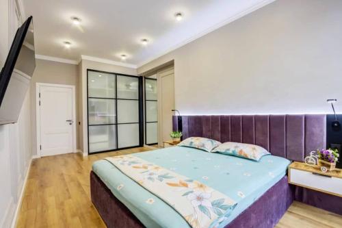 a bedroom with a large bed with a purple headboard at Coco Chanel Apartment in Bishkek in Bishkek