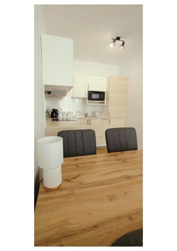 a dining room table with two chairs and a kitchen at Apartament Blask, w zaciszu zieleni z ogródkiem in Bydgoszcz