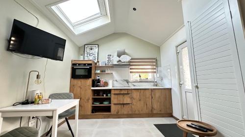 a kitchen with a table and a tv in a room at Slapen bij de Zeeuwse Lala in IJzendijke