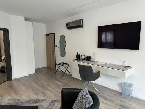 a living room with a desk and a television on a wall at Hotel Andante Rust in Rust