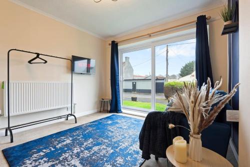 a living room with a large window and a blue rug at Perfect for Contractors Deal, 4BR House, 6BD, City Center, Free WiFi, Parking in Huntspill