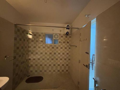 a bathroom with a shower with a tiled wall at The Grand Ganga, Peaceful, Homely, Near Sangam in Prayagraj