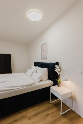 a white bedroom with a bed and a table at Das MONTI - Deluxe in Stendal