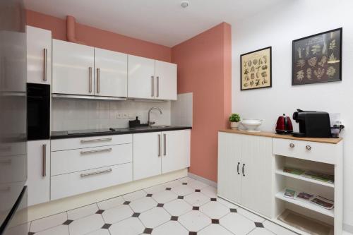 une cuisine avec des armoires blanches et des appareils noirs dans l'établissement La Kokot d'Alsace 2P centrę ville proximité Cathédrale, à Strasbourg